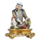 A Chinese polychrome figure, depicting a seated Lohan monk, mounted on a gilt bronze base, H 13 (