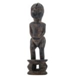 An African wooden sculpture depicting a figure standing on a stool, Luba - Congo, H 53 cm