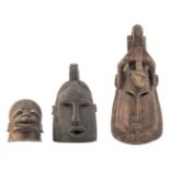 A collection of three African wooden masks, two of which helmet masks and one mask polychrome