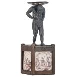 An oak box with on top an Atlas sculpture, the sides consist of four 18thC manganese decorated Dutch