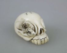 NETSUKE SCHLANGE UND SCHÄDEL, wohl Elfenbein, 19./20. Jh. Aus dem rechten Schädelauge sich