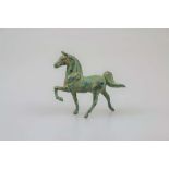 Kleine Statuette eines stolz trabenden Pferdes, grün patinierter Metallguss, H. 8 cm.