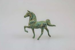 Kleine Statuette eines stolz trabenden Pferdes, grün patinierter Metallguss, H. 8 cm.