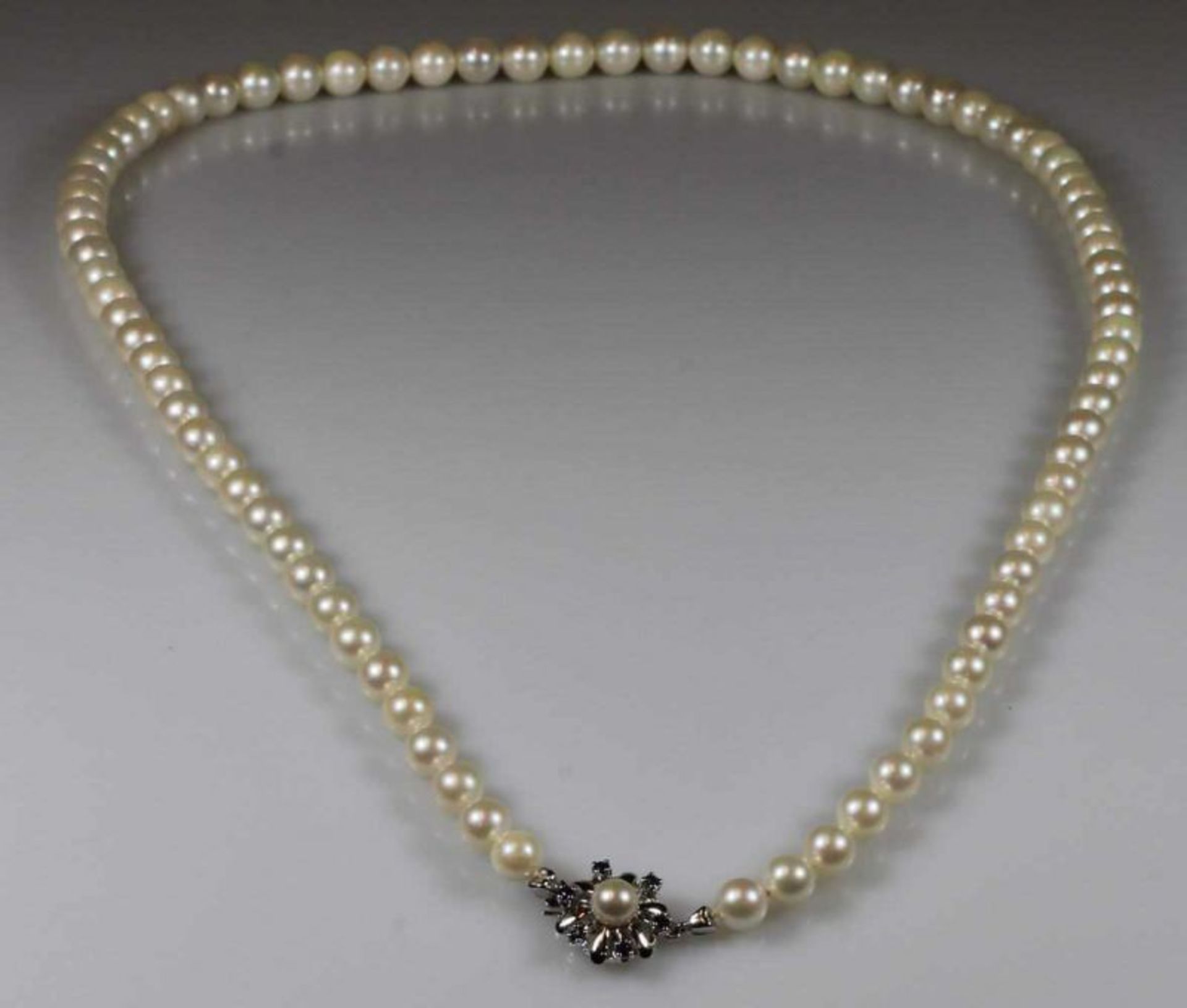 Perlenkette, 83 Akoya-Zuchtperlen ø ca. 7 mm, Schließe WG 585, 1 Perle, 6 Saphire, 62 cm lang 25.