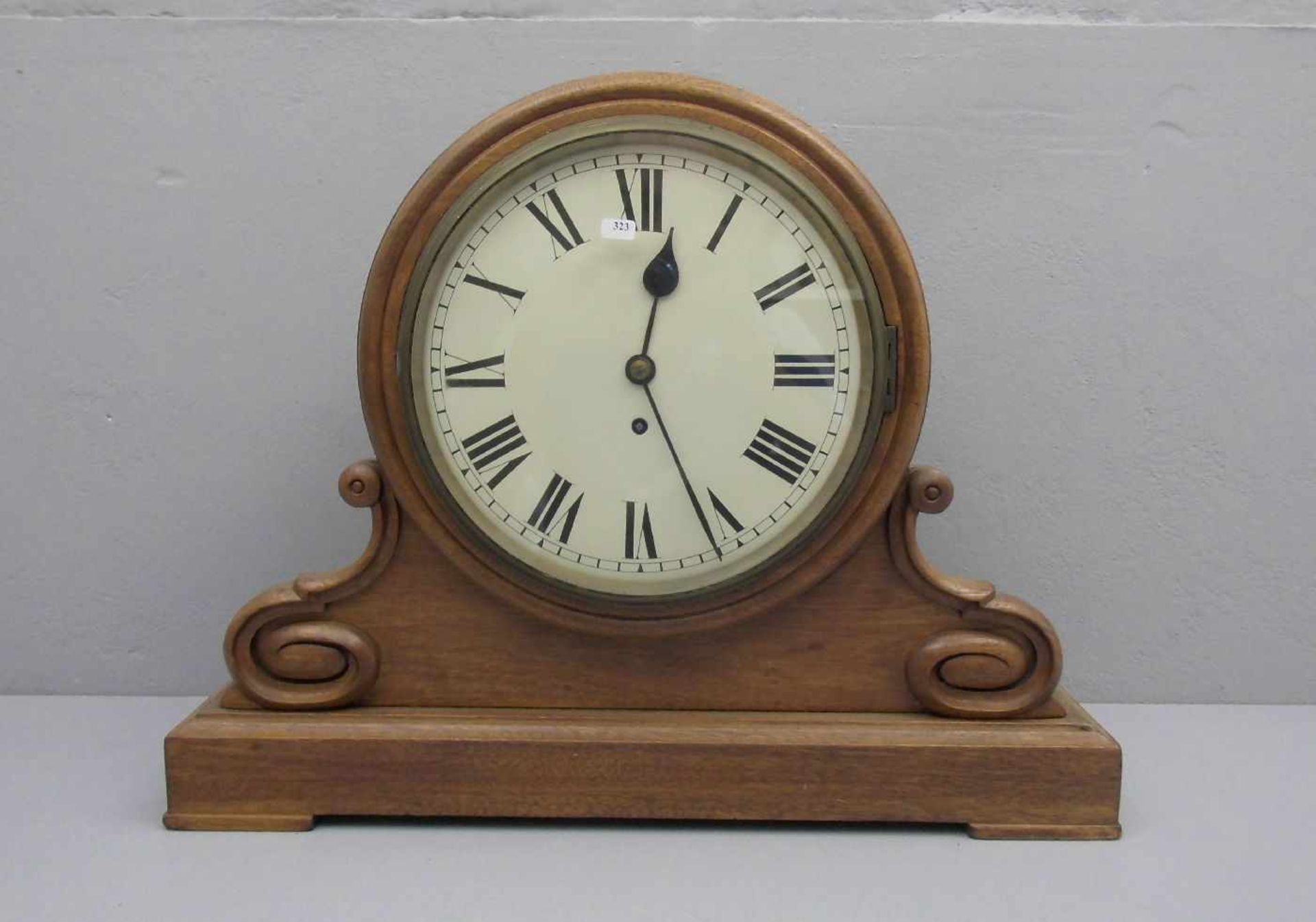 KAMINUHR / fire place clock, im gebogten Gehäuse mit plastischem Volutendekor. Lackiertes