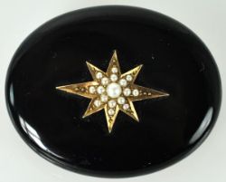 BROSCHE/ANHÄNGER oval, Onyxplatte mittig mit aufgelegtem Stern, besetzt mit feinen Perlchen,