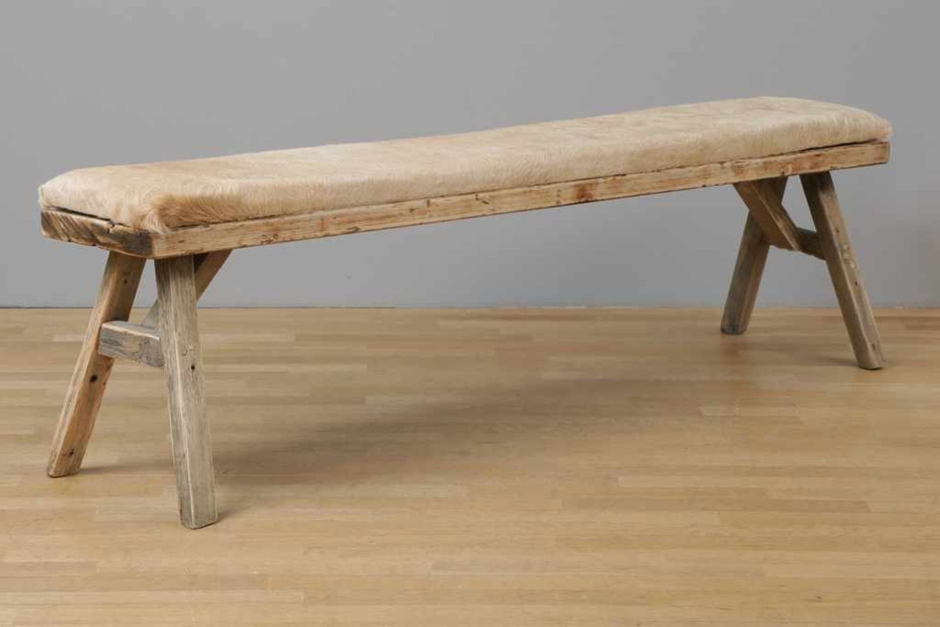 Große Sitzbank Holz und Fell, eckige, lange Sitzfläche mit hellem (Kuh?)-Fell-Bezug auf 4-beinigem