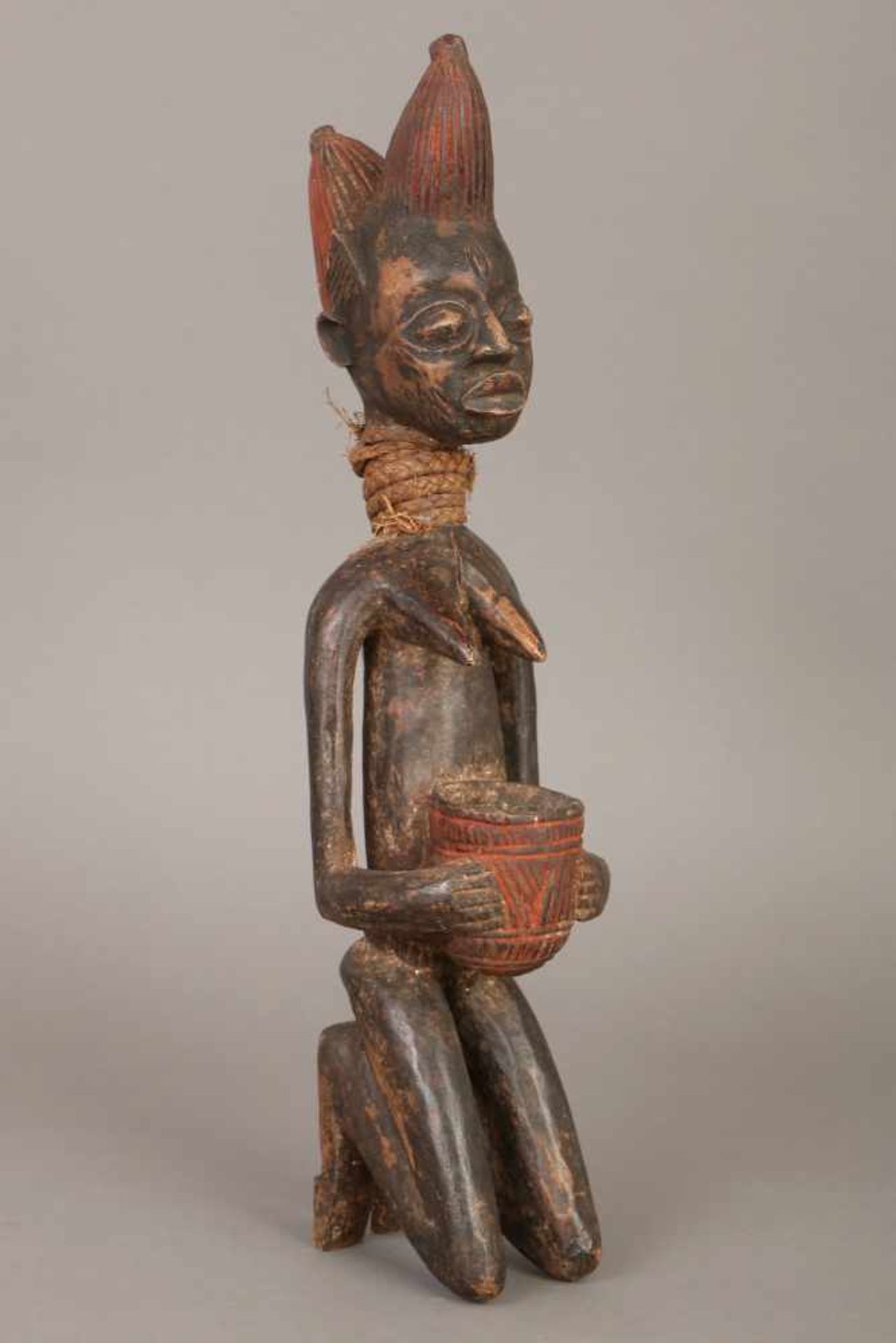 Afrikanische Ahnenfigur der Yoruba (Nigeria)Holz, dunkel patiniert, und Rafia-Geflecht, kniende