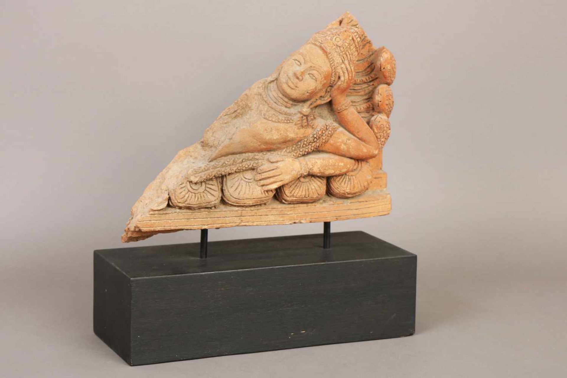 Dekoratives asiatisches Relief/Fragment ¨Liegende Gottheit¨rötlicher Steinguss, auf Holzsockel, H (