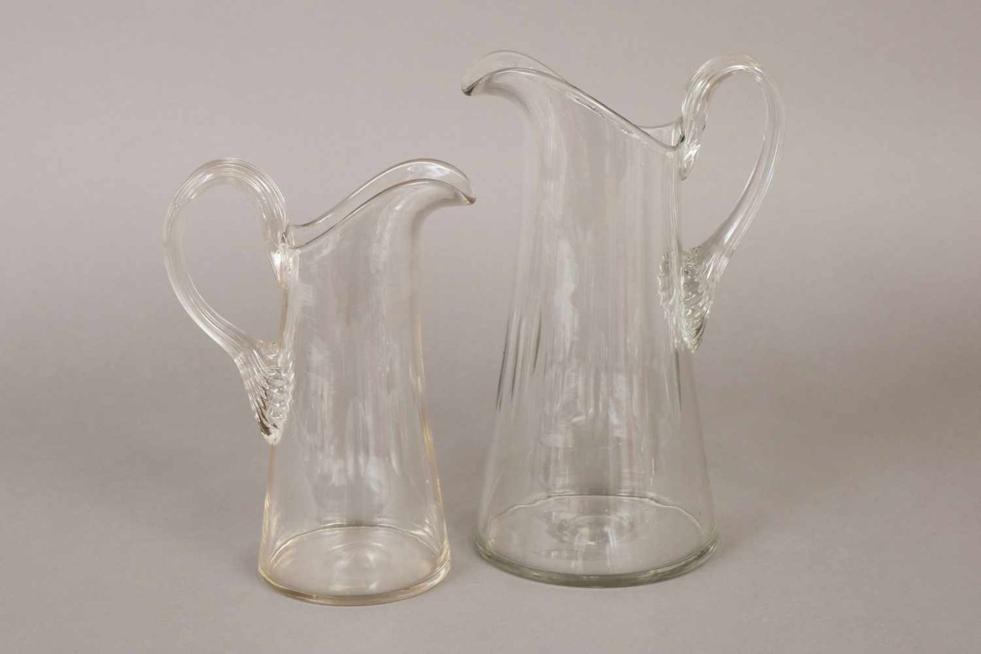 Paar Glaskrügefarbloses Glas, konischer Korpus mit breitem Ausguss, ohrenförmiger Henkel, gerippt,