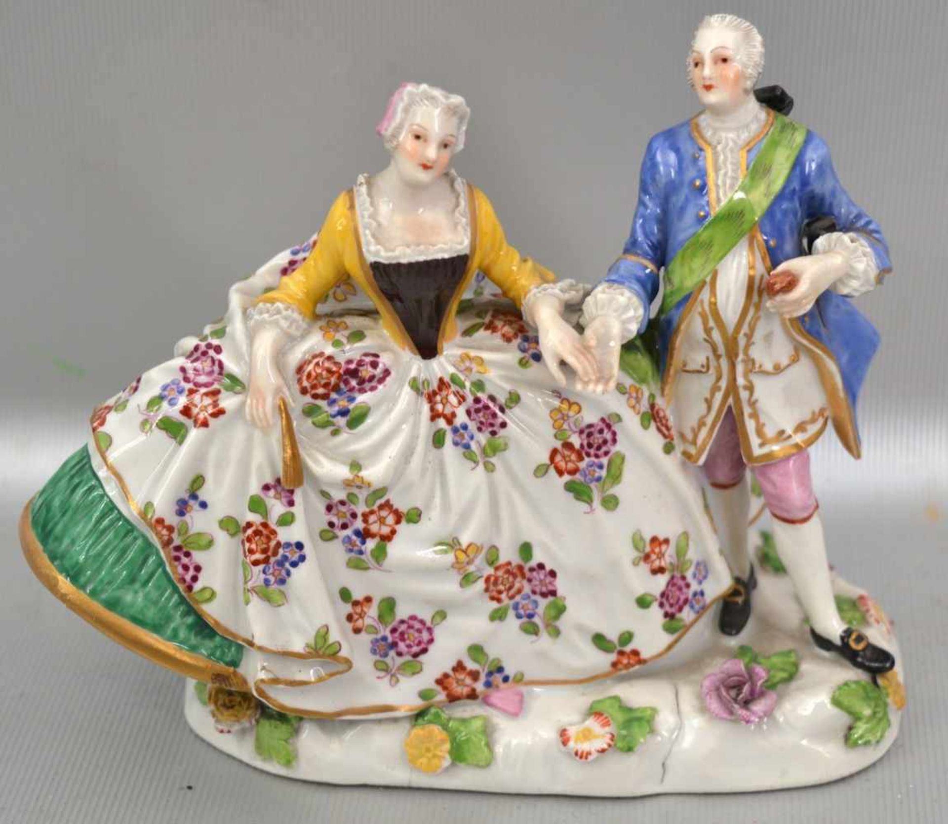 Elegantes Paar auf ovalem Sockel stehend, mit halbplastischen Blüten, leicht best., bunt bemalt, H