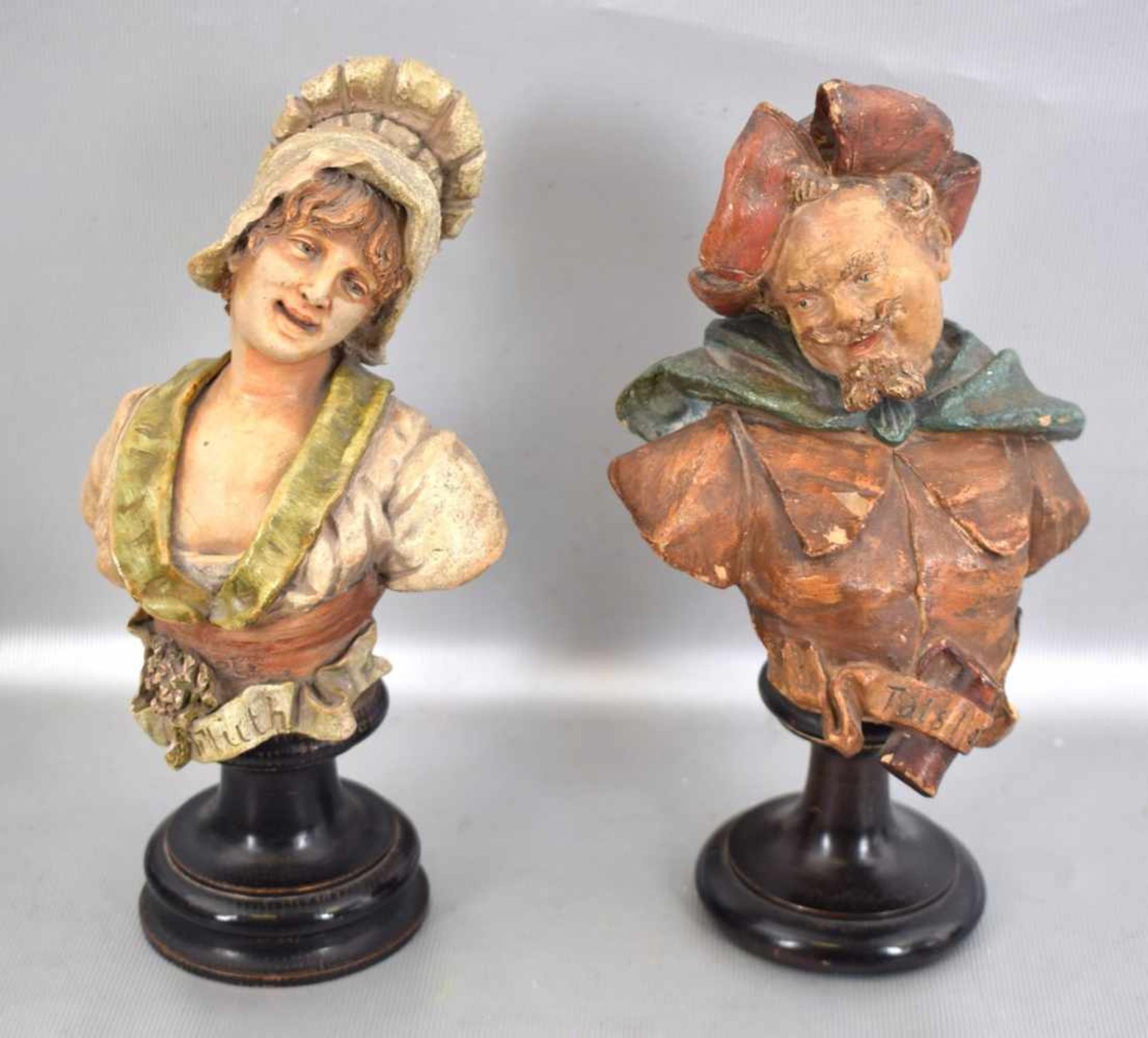 Figurenpaar Büste eines Mannes mit Hut und einer Frau mit Haube, auf rundem schwarzen Holzsockel,