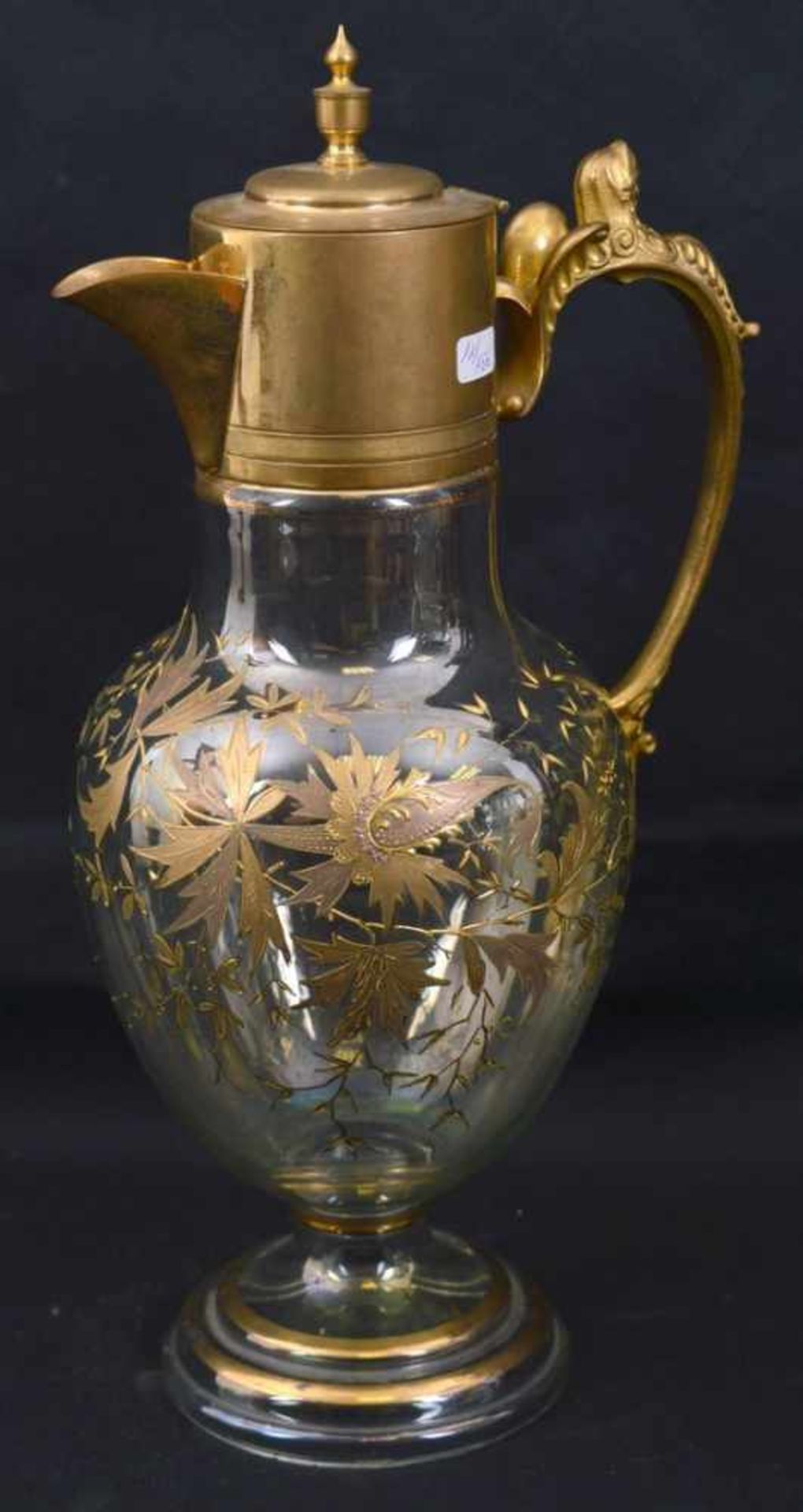 Saftkrug farbl. Glas, runder Fuß, Wandung mit goldenen Blumenranken verziert, Griff und Ausgießer