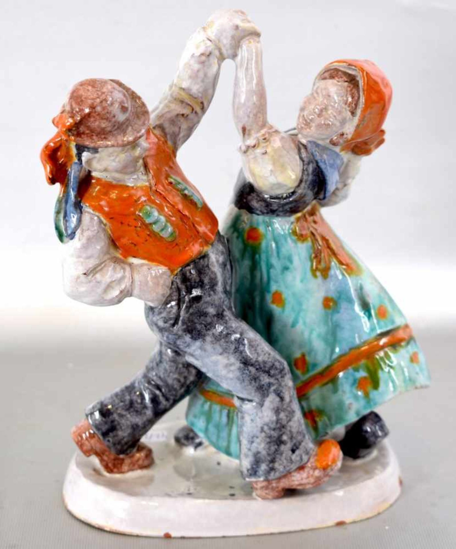Tanzendes Bauernpaar auf ovalem Sockel stehend, roter Ton, bunt bemalt, H 23 cm