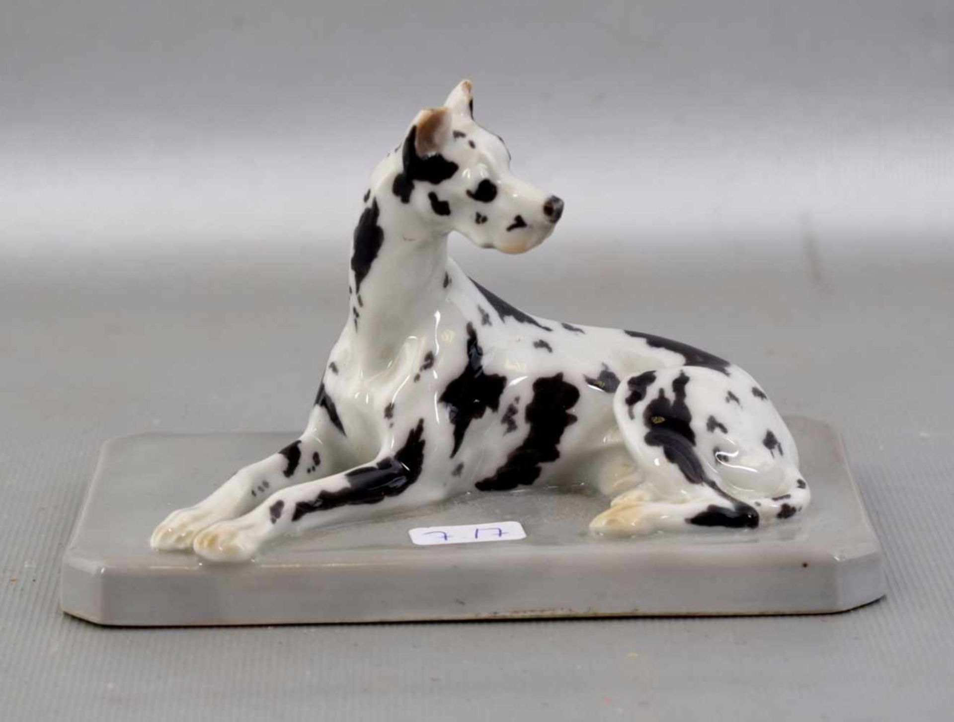 Liegende Dogge auf Sockel liegend, bunt bemalt, am Ohr besch., 12 X 7 cm, FM Heubach