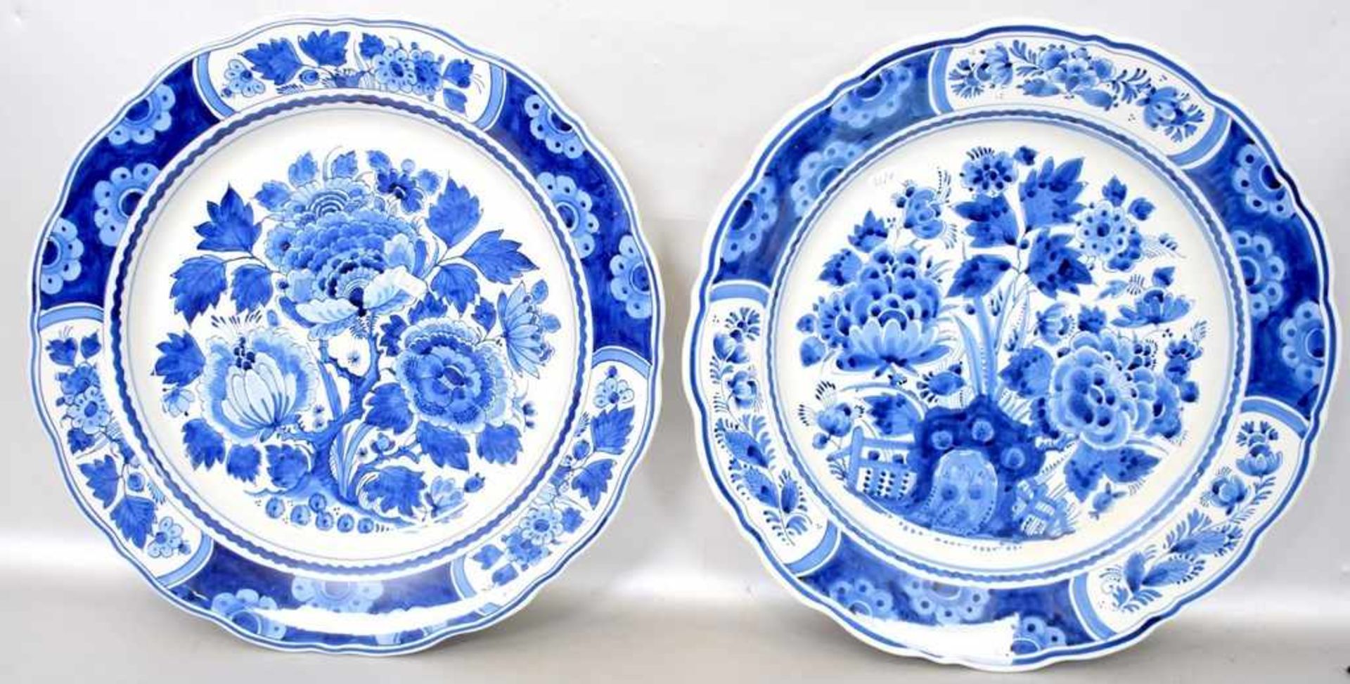 Zwei Tellerrund, breiter mit Blumen verzierter Rand, Spiegel blau bemalt, Dm 37 cm, FM Delft