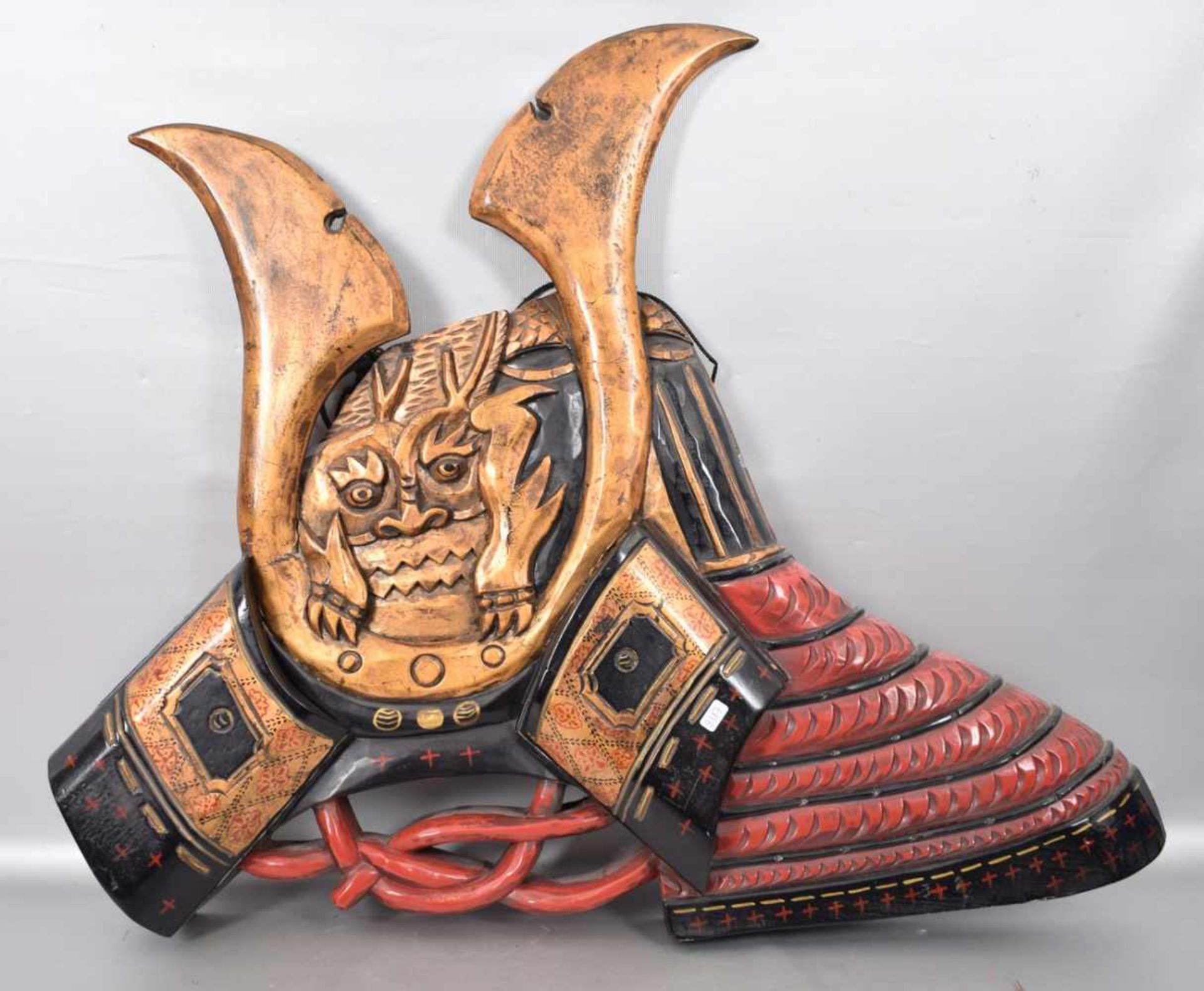 Samurai-Kabuto-DarstellungHartholz, geschnitzt, rot und gold gefasst, H 58 cm, B 70 cm