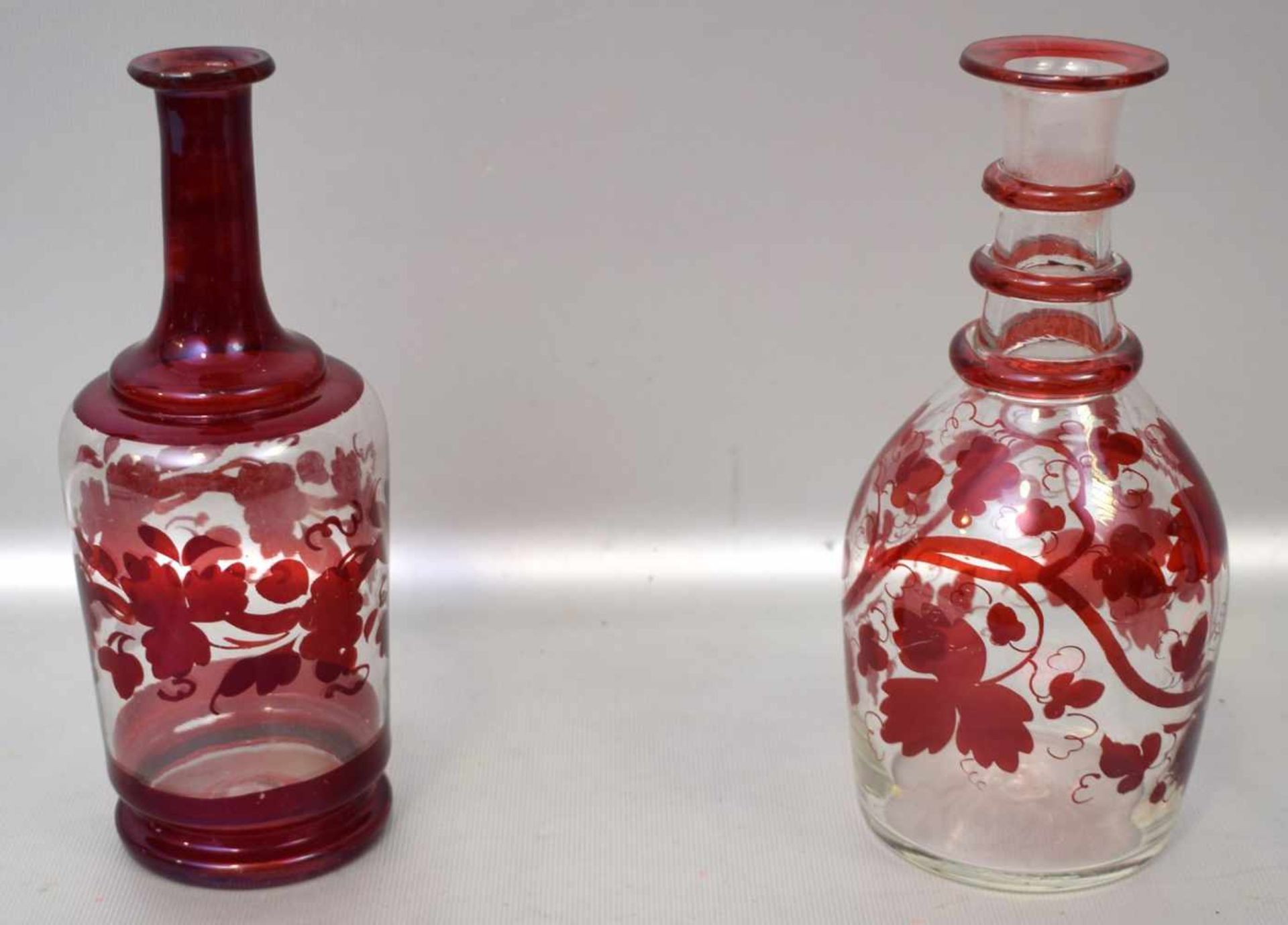 Zwei Karaffenfarbl. Glas, rund, mit rotem Überfang, H 20 cm, 19. Jh.
