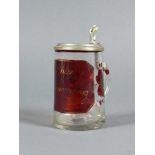Kleiner Henkelkrug (1.H.19.Jh.) farbloses Glas; frontseitig auf rotem Grund beschriftet: "Zur