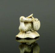 Netsuke (Japan, um 1900) "Pelikan mit Schildkröte"; Elfenbein; Bodenunterseite sign.; 3 x 4 x 3 cm