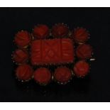 A Victorian carved coral mourning brooch,central rectangular panel surrounded by ten smaller round,