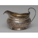 A George III silver half fluted cream jug, scroll handle, gadrooned rim, gilt interior, 11.