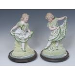 A pair of Gebruder Heubach porcelain figures, of young girls in dancing poses, in tones of green,