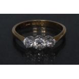 A diamond trilogy ring, central round brilliant cut diamond flanked by smaller conforming stones,