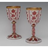 A pair of 19th century cranberry and white overlaid goblets, etched with flowers and foliage,