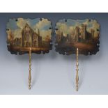 A pair of Victorian papier mache face screens, painted with abbey ruins, turned gilt sticks,