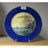 A Cauldon plate, painted with boats of a rocky coast, the rim in mottled blue, 26.