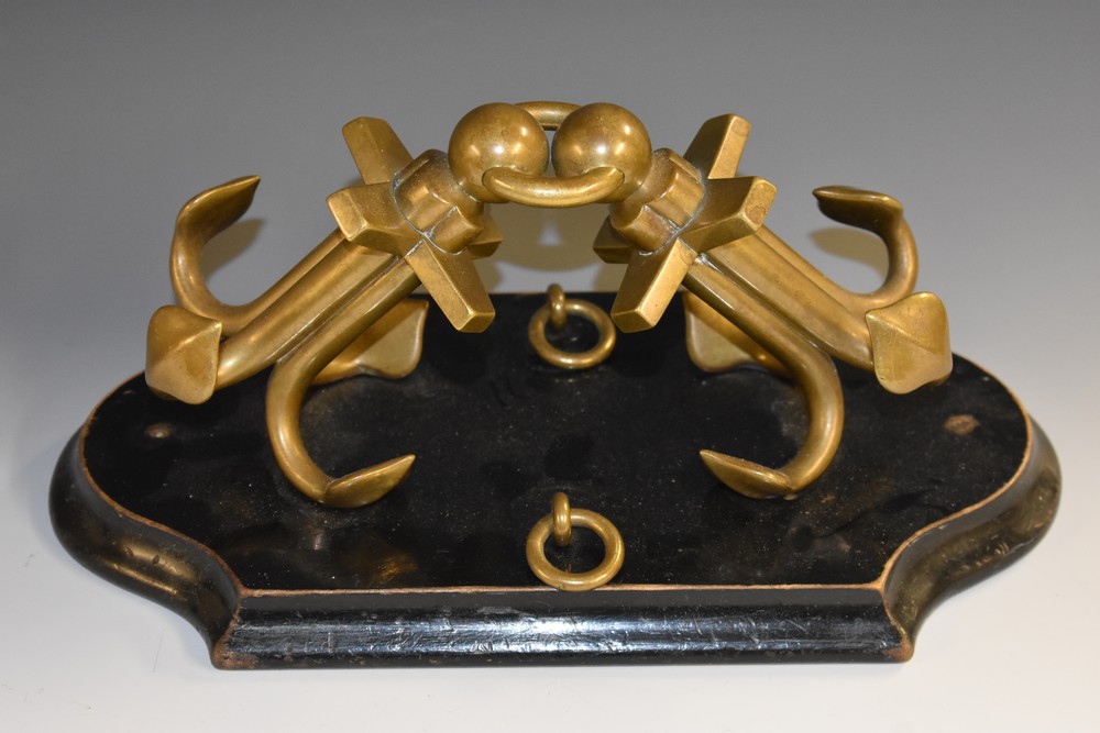 A 19th century lacquered brass maritime desk model, of a pair of anchors, shaped ebonised base,