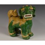 A Chinese model of a temple lion, glazed in tones of green and yellow,