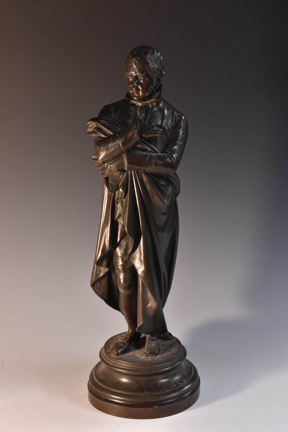 A 19th century bronzed spelter library figure, of Sir Walter Scott, he stands holding a pen,