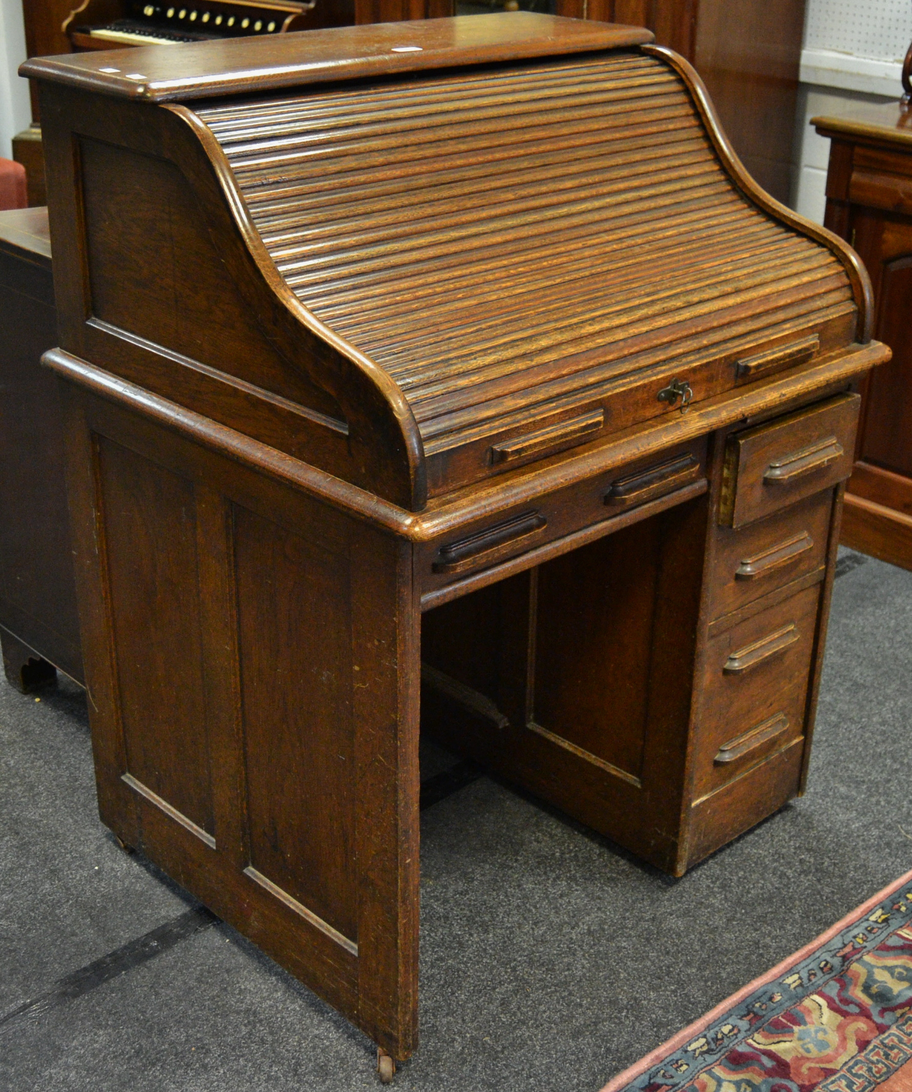 An early 20th century oak tambour fronted kneehole desk, single drawer to frieze,