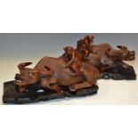 A pair of Chinese hardwood carvings, of boys astride water buffaloes,