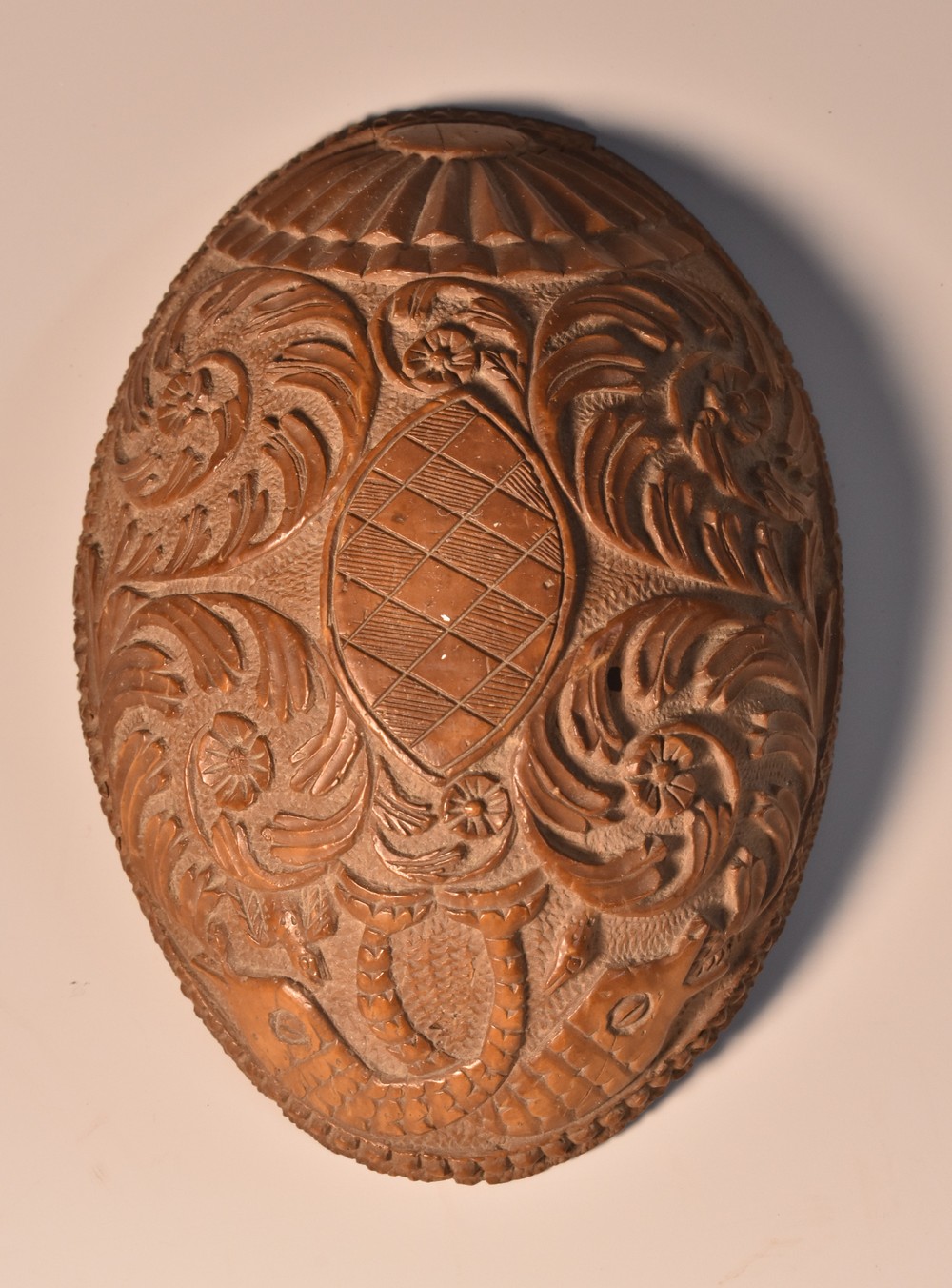 An 18th century coconut drinking bowl, carved with dolphins and scrolling foliage,