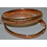 A 9ct rose gold hinged bangle, engraved and chased with scrolls, 6cm diam; 15.