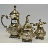 A silver coloured three piece tea service, embossed with fruiting vine, pierced finial ,