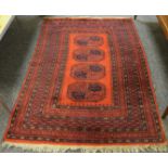 A hand woven Persian rug in tones of burnt ochre and burgundy