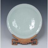 A Chinese celadon circular dish, quite plain, incised with two leaves on a ground of wavy nets,