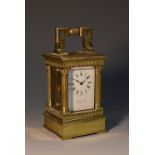 A late 19th/early 20th century brass miniature carriage clock, the white face with Roman numerals,