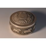 An Indian silver circular box and cover, chased with bands of animals, on a textured ground,