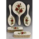 An Elizabeth II silver and enamel five piece dressing table set, comprising a hand mirror,