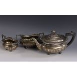 A George V silver three piece half fluted boat shaped tea service, comprising teapot,