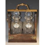 A Victorian Neo-Gothic brass-mounted oak two-bottle tantalus,