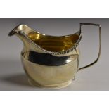 A George III silver boat shaped cream jug, gadrooned rim, reeded angular scroll handle,