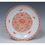 A Chinese dish, decorated in in red with lotus and scrolling foliage, the rim with bats,