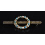 A turquoise and half pearl yellow metal brooch,