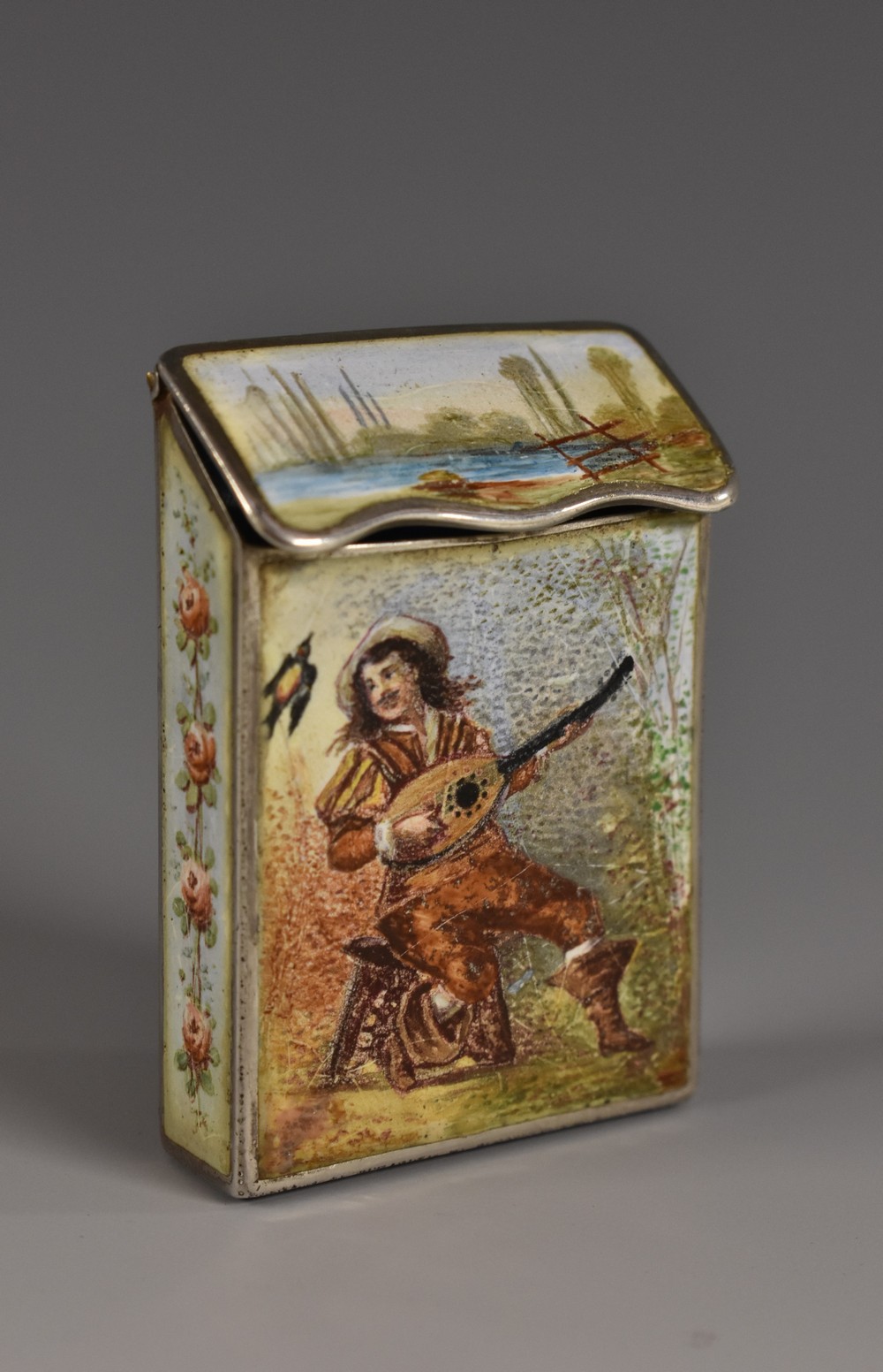 A Continental silver and enamel vesta case, decorated in polychrome with serenading sweethearts,